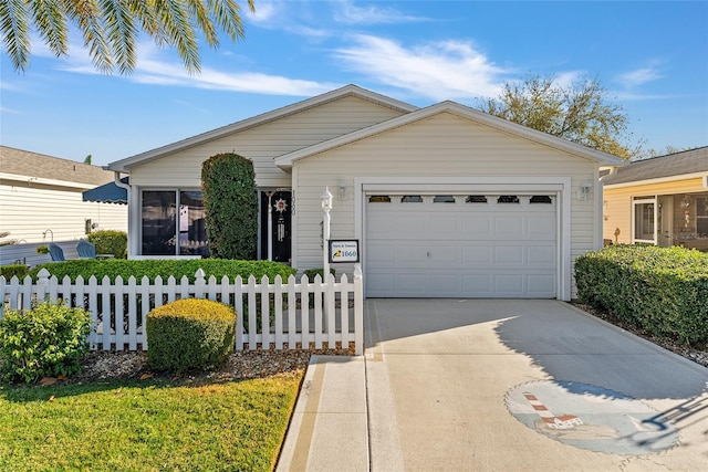 ranch-style house featuring a fenced front yard, an attached garage, and driveway