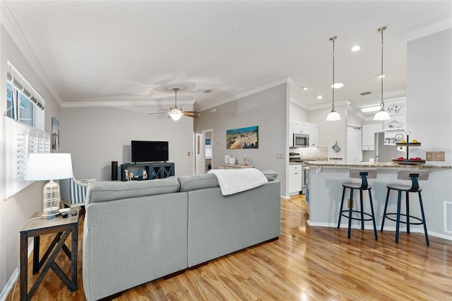 living area with light wood-type flooring, visible vents, recessed lighting, crown molding, and ceiling fan