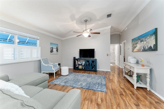 living room featuring visible vents, wood finished floors, baseboards, and ornamental molding