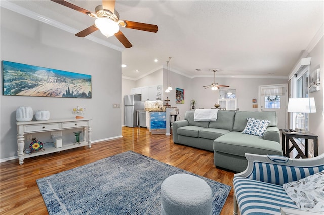 living area with baseboards, light wood finished floors, ceiling fan, ornamental molding, and vaulted ceiling