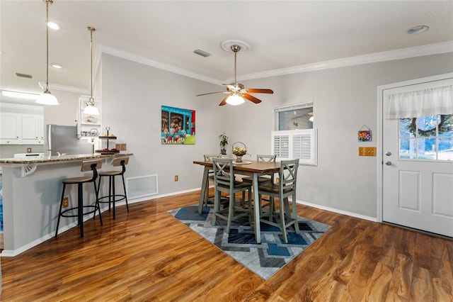 dining space with visible vents, wood finished floors, and ornamental molding