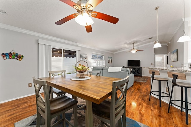 dining room featuring dark wood finished floors, vaulted ceiling, a textured ceiling, and ornamental molding