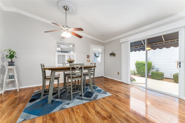 dining area featuring ornamental molding, baseboards, lofted ceiling, and wood finished floors