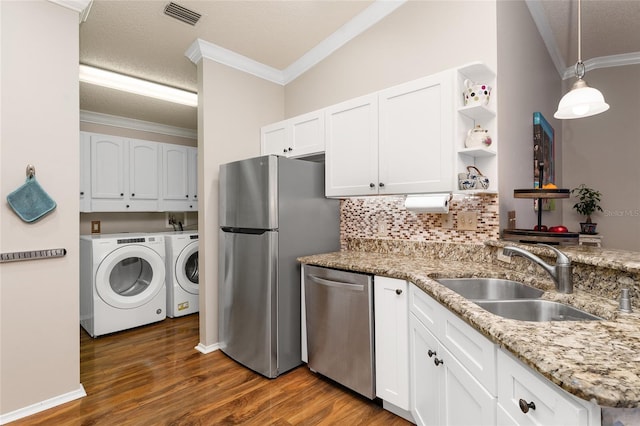 kitchen with visible vents, a sink, washing machine and dryer, stainless steel appliances, and crown molding