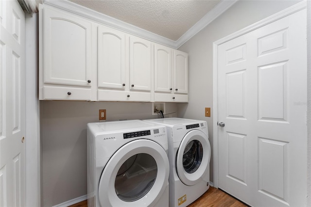 clothes washing area with washer and dryer, a textured ceiling, cabinet space, light wood-style floors, and crown molding