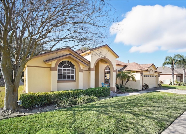 mediterranean / spanish-style home featuring an attached garage, a front lawn, concrete driveway, and stucco siding