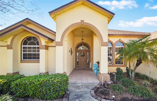 doorway to property with roof with shingles and stucco siding