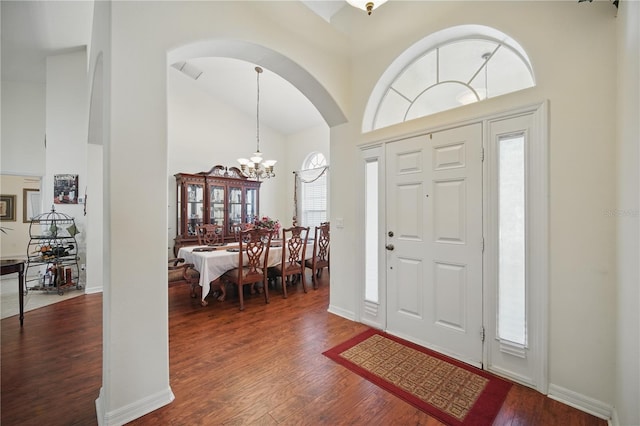 entrance foyer with dark wood-style floors, visible vents, a towering ceiling, an inviting chandelier, and baseboards