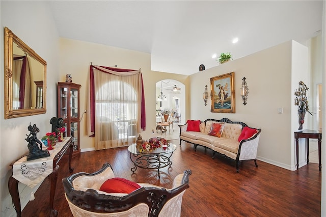 living area with arched walkways, wood finished floors, a ceiling fan, and baseboards