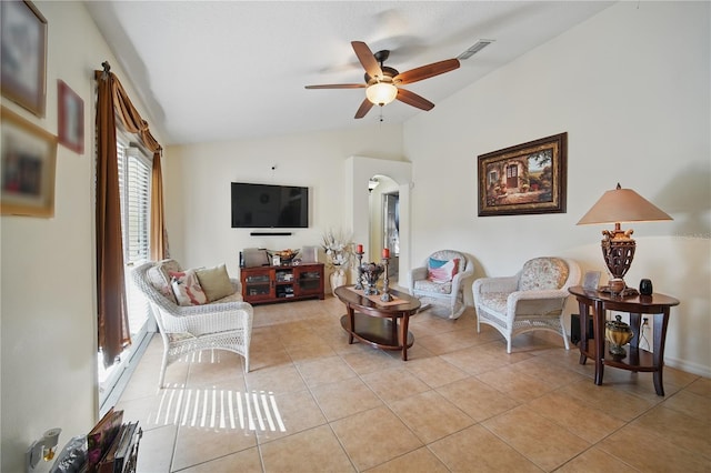 living area featuring lofted ceiling, light tile patterned floors, ceiling fan, and arched walkways