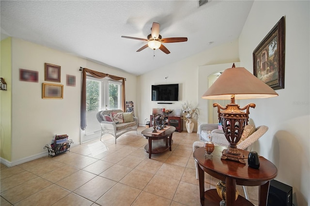 living room featuring baseboards, a ceiling fan, vaulted ceiling, a textured ceiling, and light tile patterned flooring