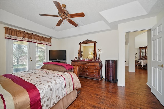 bedroom featuring arched walkways, a raised ceiling, wood finished floors, access to outside, and a textured ceiling