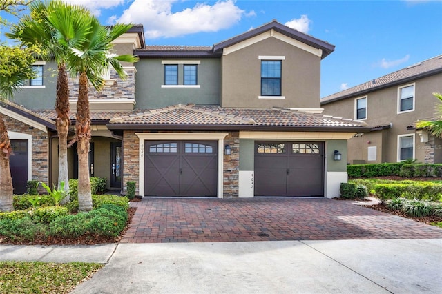 view of property with an attached garage, stone siding, decorative driveway, and stucco siding