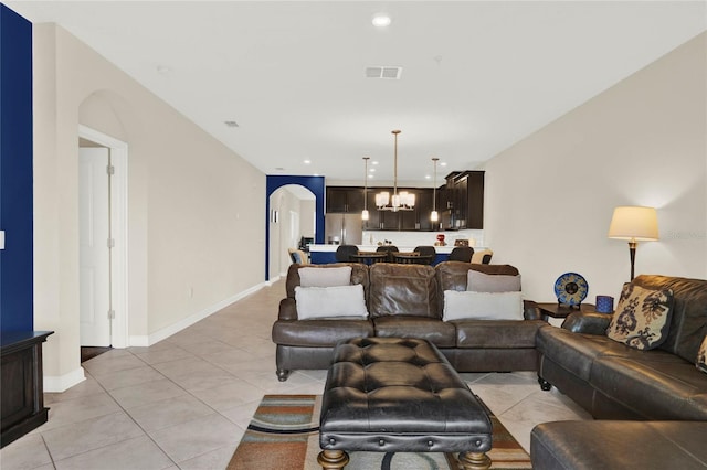 living area with light tile patterned floors, visible vents, arched walkways, a notable chandelier, and recessed lighting