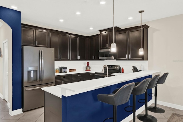 kitchen featuring light tile patterned floors, a breakfast bar area, a peninsula, light countertops, and appliances with stainless steel finishes