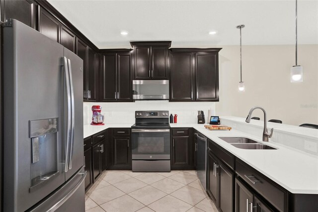 kitchen with a peninsula, appliances with stainless steel finishes, a sink, and light countertops