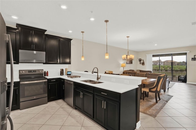 kitchen with a sink, stainless steel appliances, dark cabinets, and open floor plan