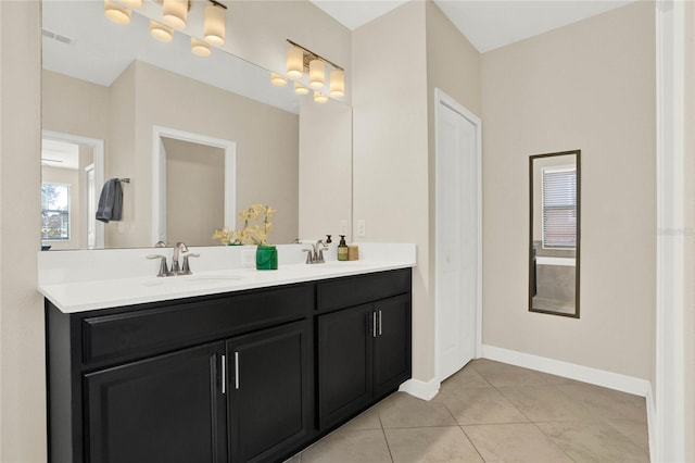 bathroom with tile patterned flooring, a sink, visible vents, baseboards, and double vanity