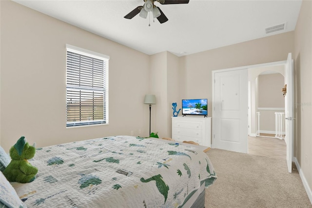 carpeted bedroom featuring visible vents, arched walkways, ceiling fan, and baseboards