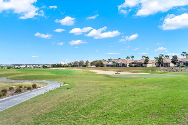 surrounding community with view of golf course, a lawn, and a residential view