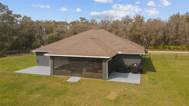 rear view of property featuring a forest view, a sunroom, fence, and a yard