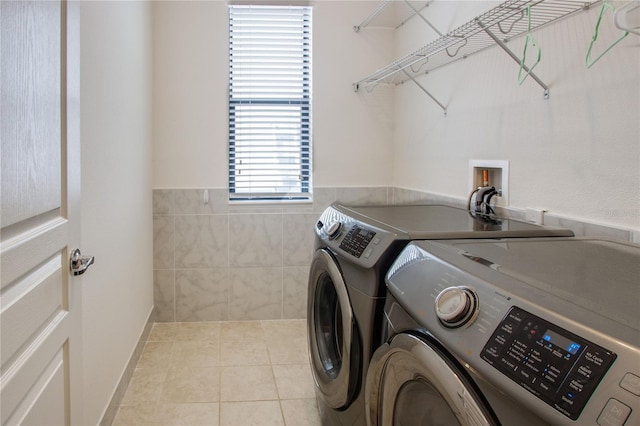 washroom with washing machine and clothes dryer, laundry area, tile patterned flooring, and tile walls