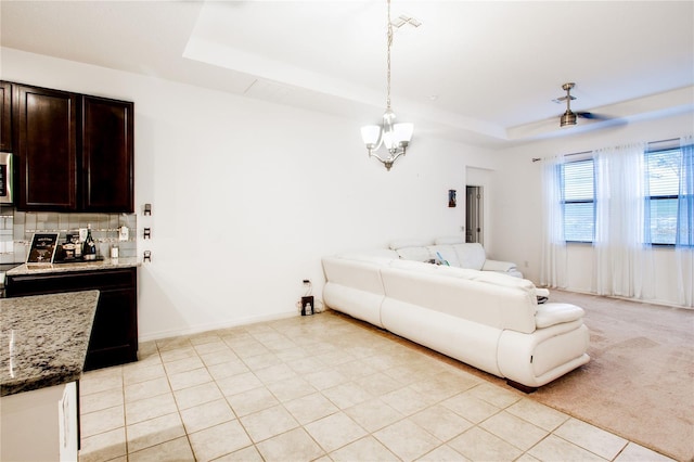 interior space featuring light tile patterned floors, a tray ceiling, baseboards, and a notable chandelier