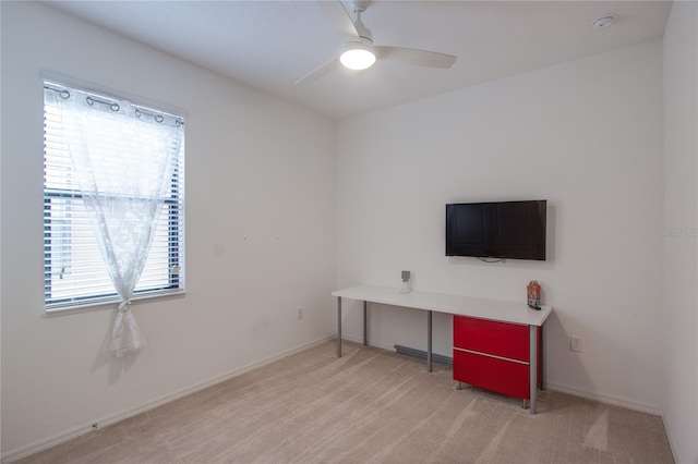 interior space with baseboards, light carpet, and a ceiling fan