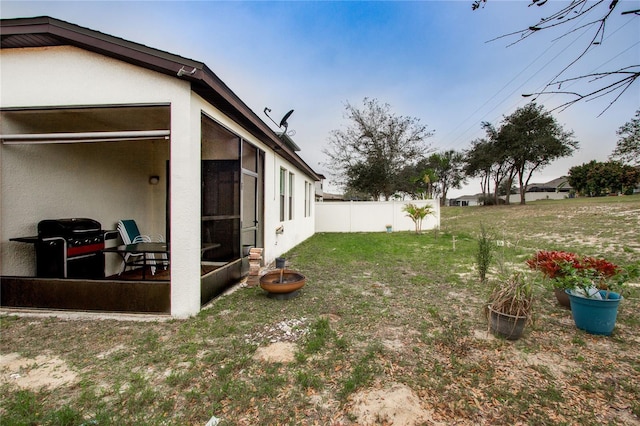 view of yard featuring fence and a sunroom