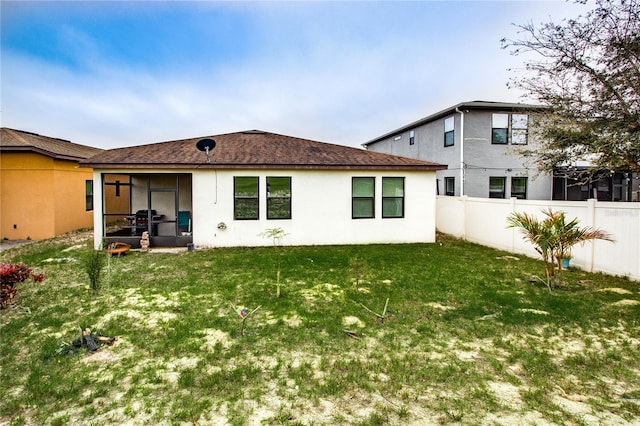 back of property featuring stucco siding, a sunroom, a yard, and fence