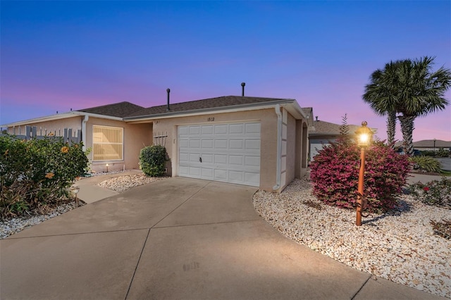 ranch-style home featuring a garage, concrete driveway, and stucco siding