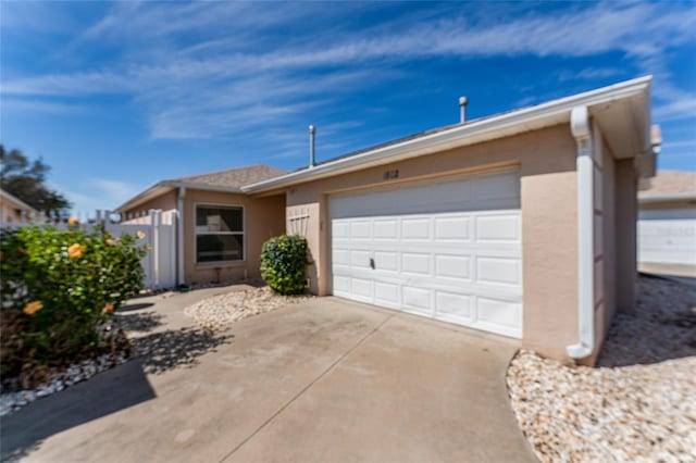 single story home featuring driveway, an attached garage, and stucco siding