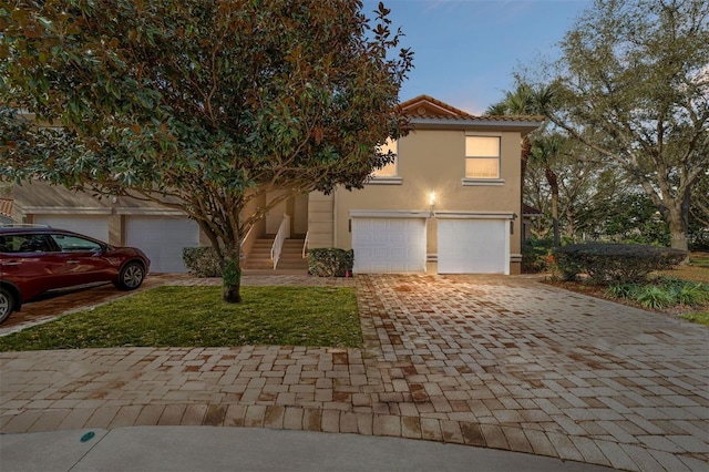 view of front of home with decorative driveway, a tile roof, and stucco siding