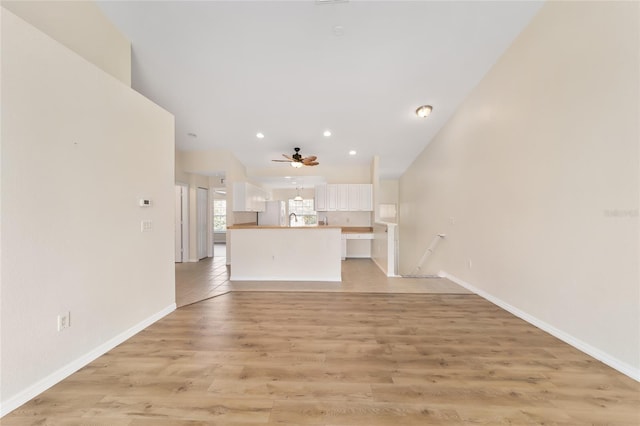 unfurnished living room featuring baseboards, a ceiling fan, light wood-style flooring, a sink, and recessed lighting