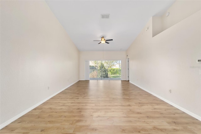 empty room featuring ceiling fan, lofted ceiling, visible vents, baseboards, and light wood-style floors