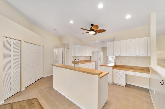 kitchen with light tile patterned floors, white fridge with ice dispenser, ceiling fan, and white cabinetry