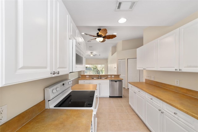 kitchen with white appliances, a sink, visible vents, and white cabinets