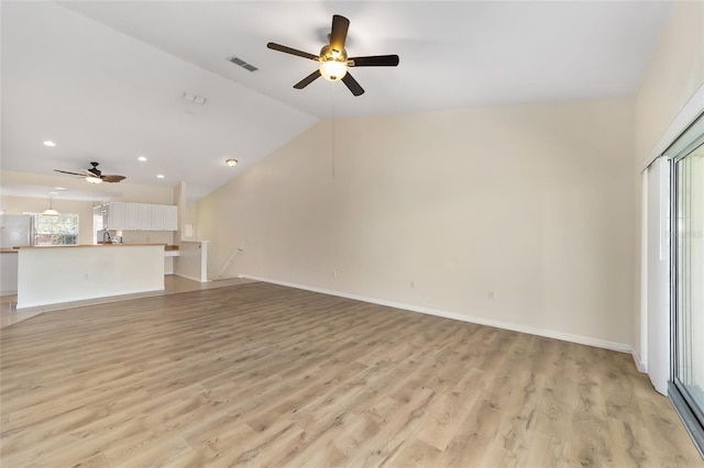 unfurnished living room with light wood-style flooring, visible vents, vaulted ceiling, and baseboards