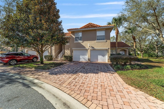 view of front of home featuring a garage, decorative driveway, a tile roof, and stucco siding