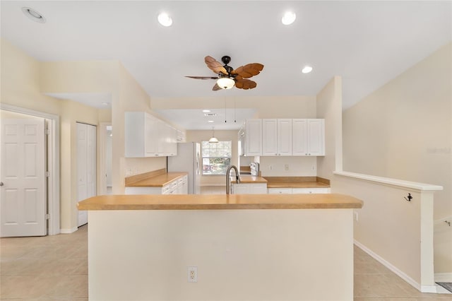 kitchen featuring light countertops, white cabinets, a sink, and freestanding refrigerator