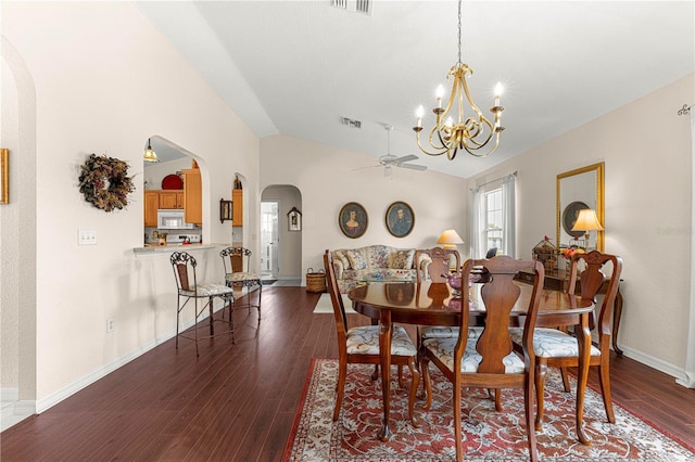 dining area with arched walkways, dark wood-style flooring, vaulted ceiling, baseboards, and ceiling fan with notable chandelier