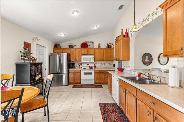 kitchen featuring brown cabinets, light tile patterned floors, light countertops, a sink, and white appliances