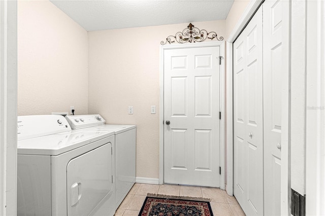 laundry area featuring light tile patterned floors, a textured ceiling, laundry area, baseboards, and washer and dryer