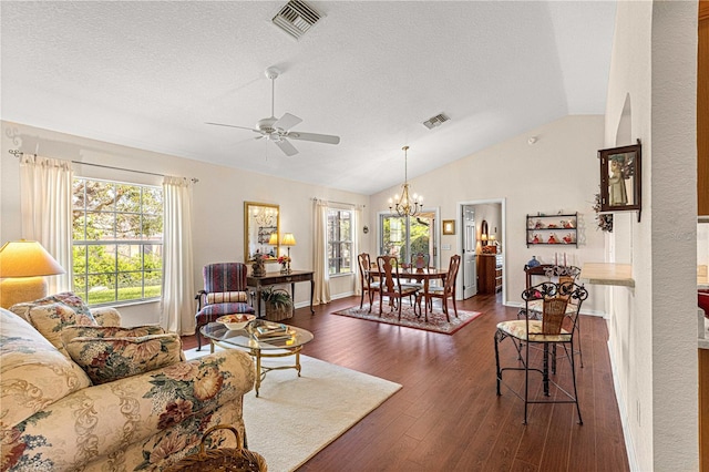 living area featuring dark wood-style floors, vaulted ceiling, visible vents, and a healthy amount of sunlight