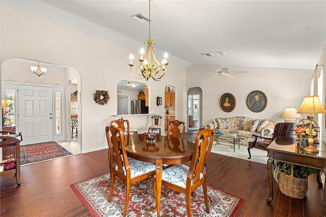 dining area featuring arched walkways, visible vents, vaulted ceiling, and wood finished floors