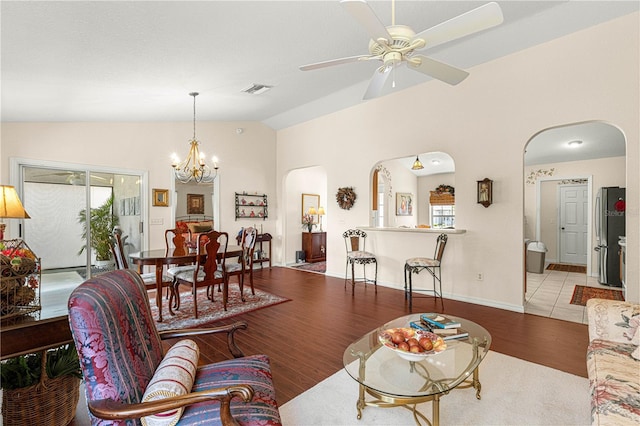 living room with arched walkways, wood finished floors, visible vents, vaulted ceiling, and a wealth of natural light