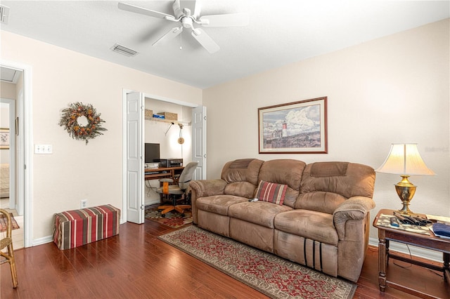 living area featuring a ceiling fan, visible vents, baseboards, and wood finished floors