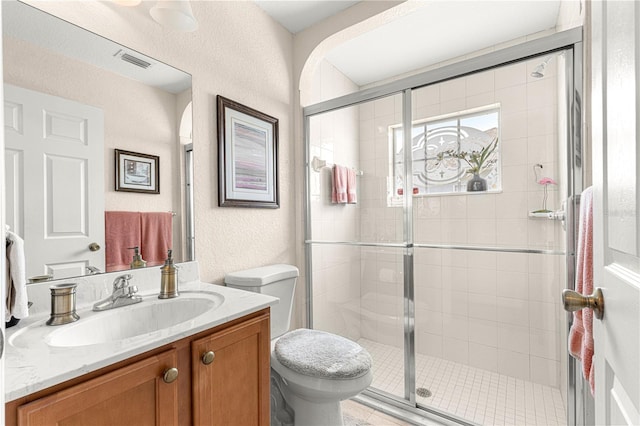 full bath with visible vents, a textured wall, toilet, vanity, and a shower stall