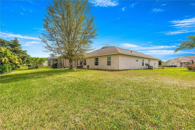 back of property featuring central air condition unit, a lawn, and stucco siding