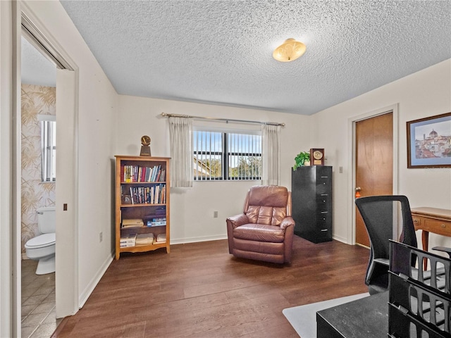 home office with a textured ceiling, wood finished floors, and baseboards